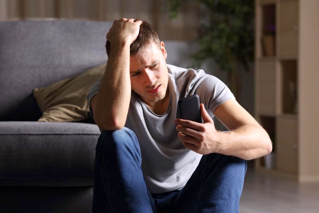 Sad man looking at a phone